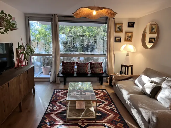 Séjour chaleureux avec canapé en cuir, tapis et grande baie vitrée