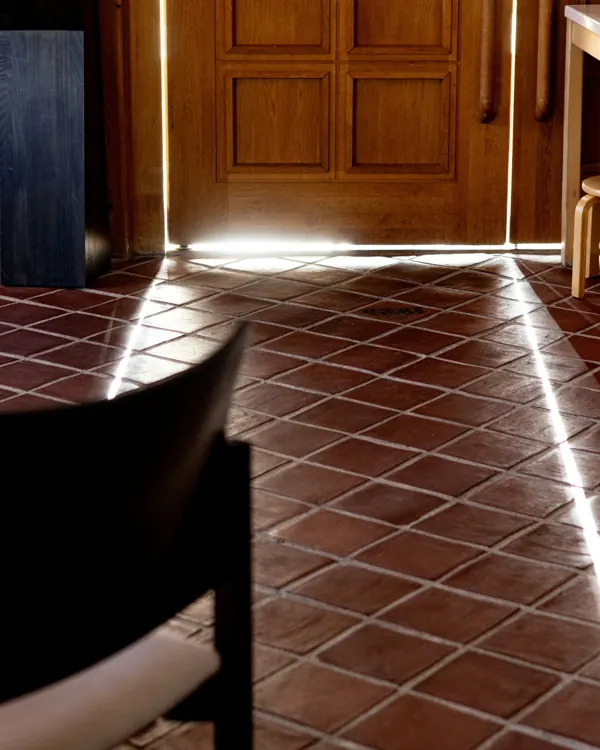 Entrée d'appartement bordelais avec sol en tomettes et porte en bois éclairée